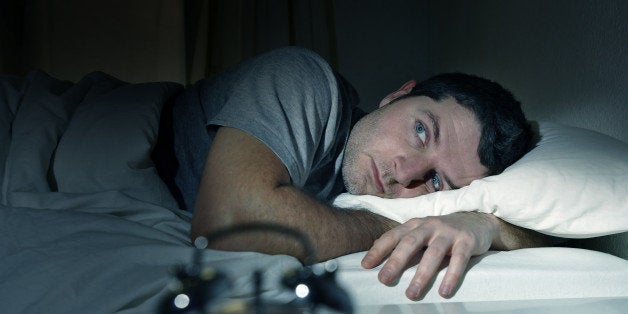 young man in bed with eyes wide opened suffering insomnia , stress and sleep disorder thinking about his problem