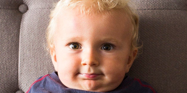 Portrait of toddler boy on couch, smiling