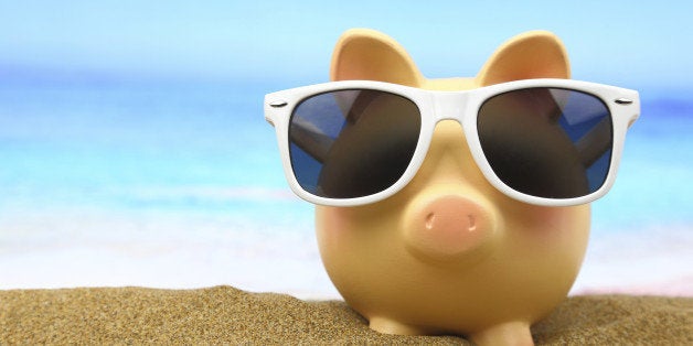 Summer piggy bank with sunglasses on the beach