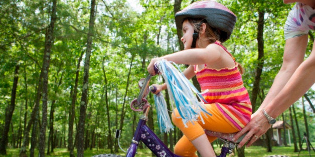 Mother helping daughter to ride bicycle