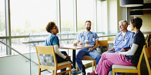 Smiling medical team in discussion during break in hospital employee lounge