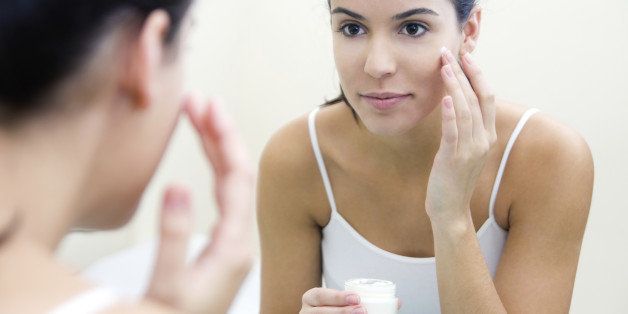 Body care. Close up portrait of Woman applying cream on face