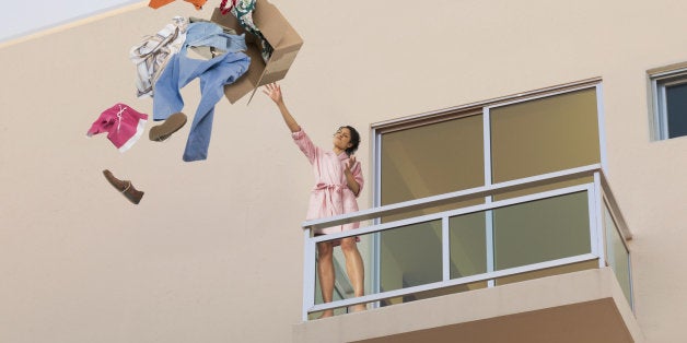 Mixed race woman throwing clothes off balcony