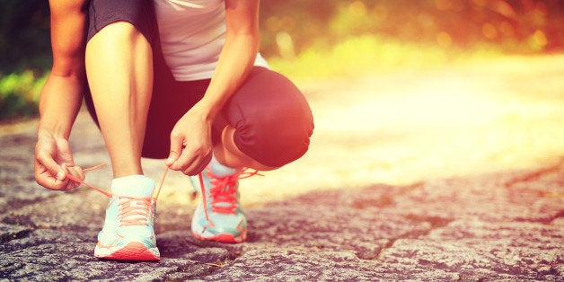 young fitness woman runner tying shoelaces on trail