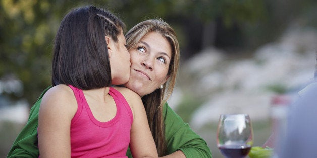 Daughter kissing mother on the cheek at garden dinner party