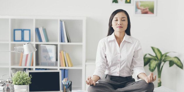 Female office worker meditating on her work place
