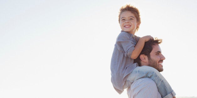 Father carrying son on shoulders on beach