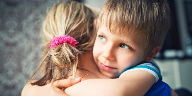 Closeup of happy little boy aged 5 embracing his mother. The mother and boy are lit by soft light from the window.