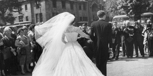 A bride and groom face the cameras after their wedding ceremony.