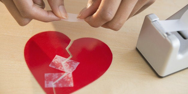 Mixed race woman taking broken paper heart