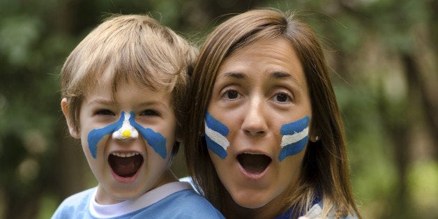 Mama e hijo, festejando un gol del seleccionado argentino. Pintados con la bandera argentina y utilizando la camiseta del mundial 2014.