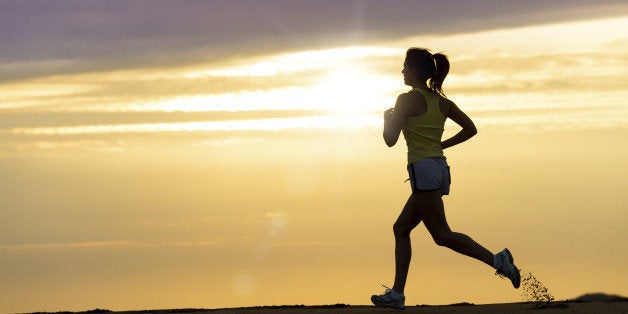 Woman running alone on beautiful sunset in the beach. Summer sport and freedom concept. Athlete training on dusk.