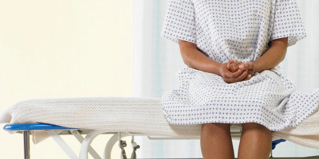 Female patient sitting on gurney in hospital gown, low section