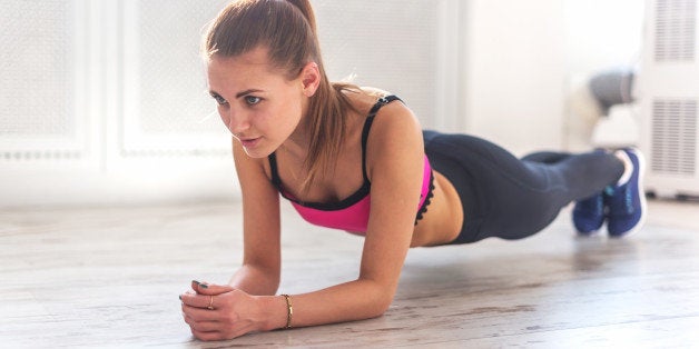 Slim fitnes young girl with ponytail doing planking exercise indoors at home gymnastics.