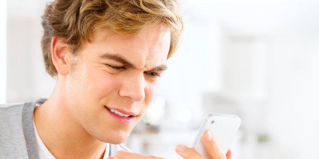 Frustrated man sending text message using mobile phone at home