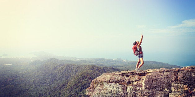 young woman hiker taking photo with smart phone at mountain peak