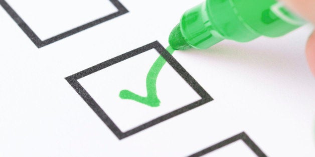 Macro shot of human hand drawing green check mark in checklist box