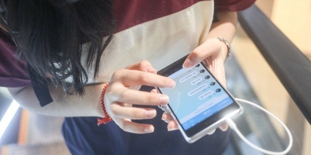 A Chinese girl chatting with WeChat on smartphone on a moving escalator in Japan