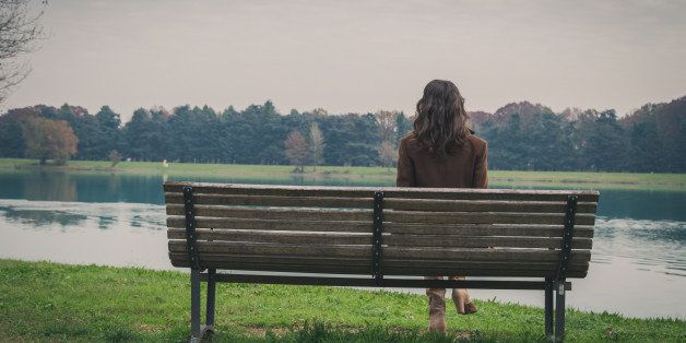 Beautiful young woman with long hair sitting on a bench in a city park