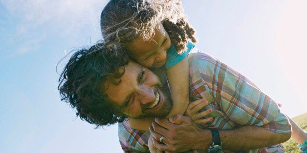 Low angle view of father carrying daughter piggyback outdoors