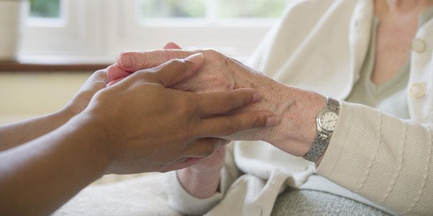 Close up of older woman and caretaker holding hands