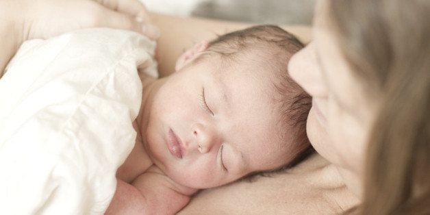 Newborn baby boy sleeping at mums chest