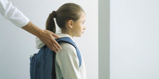 Woman's hand on shoulder of girl with backpack