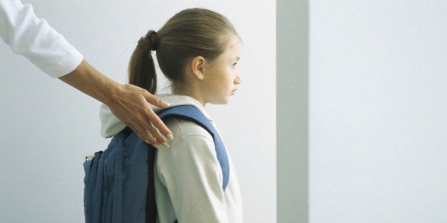 Woman's hand on shoulder of girl with backpack