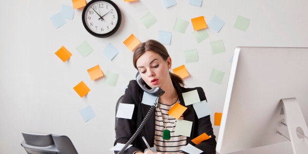 Studio shot of young woman working in office covered with adhesive notes