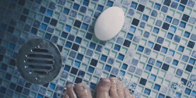 Top view of feet, soap and bubbles in shower.