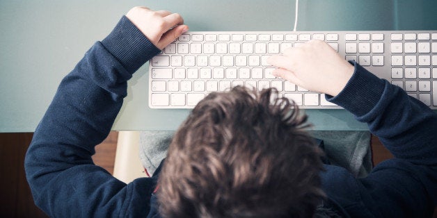 10 years old child typing on PC keyboard, sitting at a desk, shot from above. natural lighting