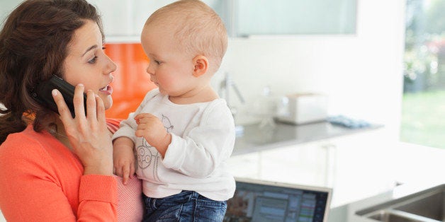 Mother holding baby and talking on cell phone