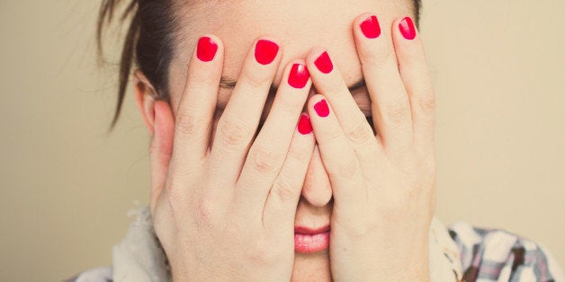 Woman closeup covering his eyes with his hands.