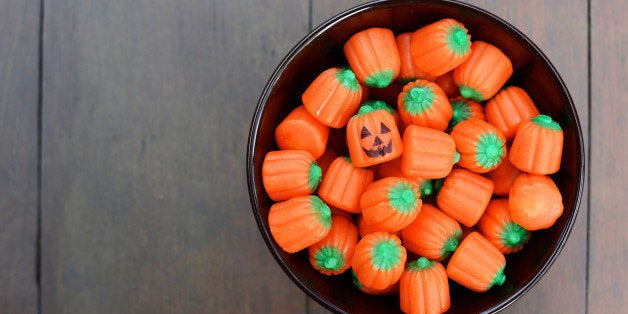 Bowl of pumpkin shaped Halloween candy. One has a jack o' lantern face.