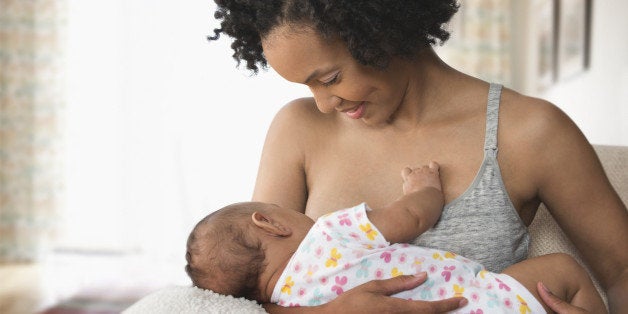 Mother breastfeeding baby in living room