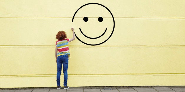 Girl drawing smiley face on to a wall