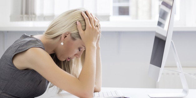 Overworked and frustrated young woman in front of computer in office.