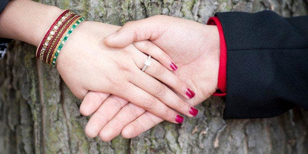 A young Indian couple's engagement hands on a sunny day outdoors.