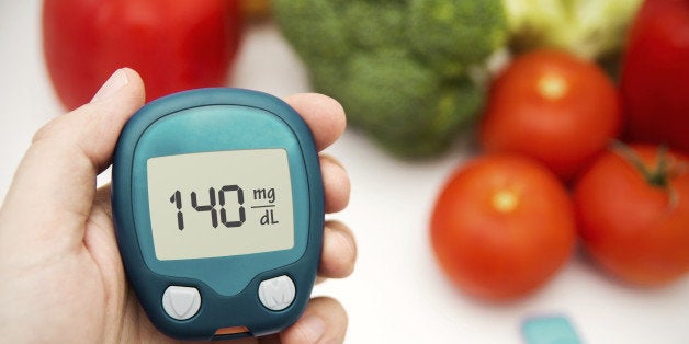 Hand holding meter. Diabetes doing glucose level test. Vegetables in background