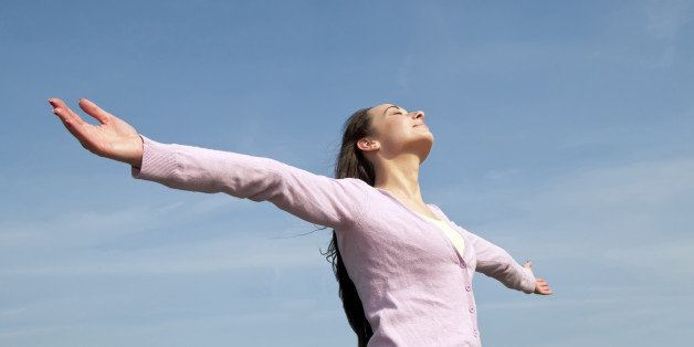 happy and healthy young woman with open arms against blue sky feeling freedom