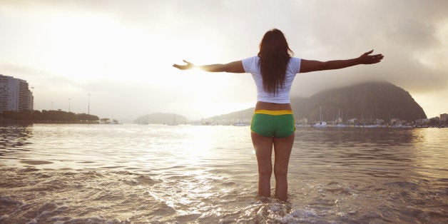 Mature woman with arms outstretched on Botafogo beach, Rio De Janeiro, Brazil