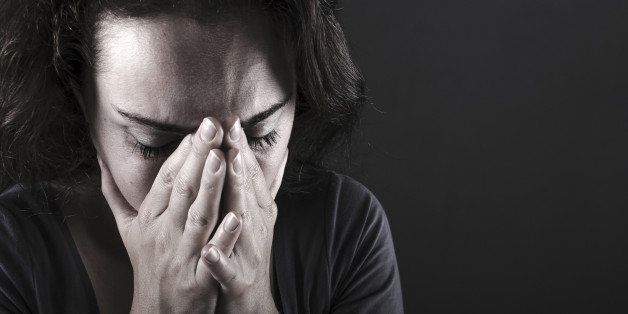 Depressed woman with hands over her face. Crying.
