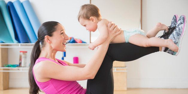 Caucasian woman holding baby on yoga mat