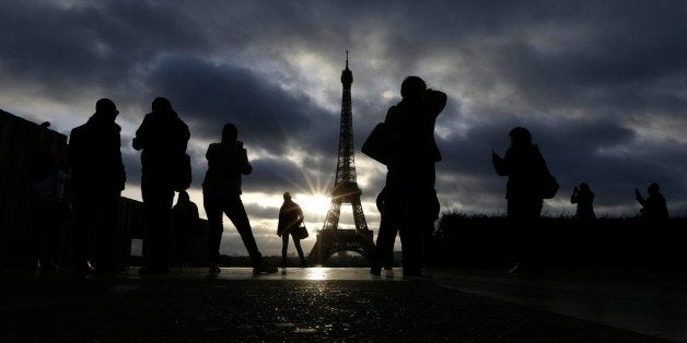 Tourists visit the site of Eiffel Tower which remained closed on the first of three days of national mourning in Paris, Sunday, Nov. 15, 2015. Thousands of French troops deployed around Paris on Sunday and tourist sites stood shuttered in one of the most visited cities on Earth while investigators questioned the relatives of a suspected suicide bomber involved in the country's deadliest violence since World War II. (AP Photo/Amr Nabil)