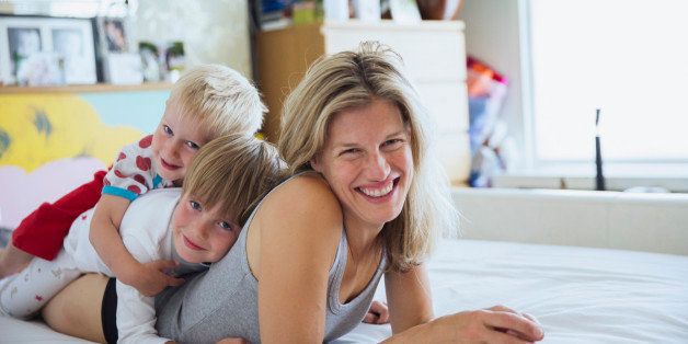 Portrait of mother with sons in bed lying one on top of another