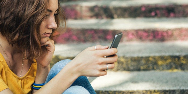 Teen girl dressed in yellow t-shirt breaking up with his boyfriend through messages. Dark toning.