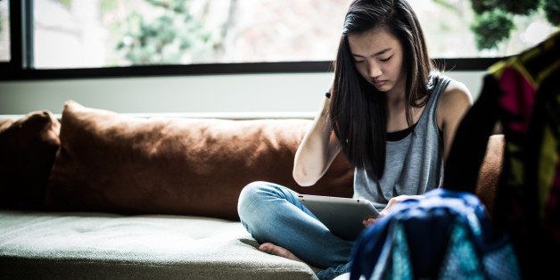 girl (13) using tablet on couch