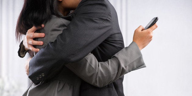 Business couple hug yet the woman still using cell phone, can be concept for busy lifestyle of cheating