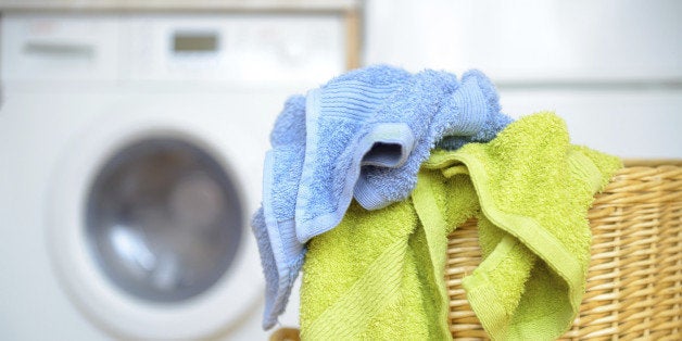 Dirty clothes basket with towels waiting for laundry with washing machine in backround