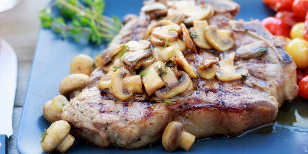 Grilled t-bone steak covered with mushrooms and a side of sauteed tomatoes.